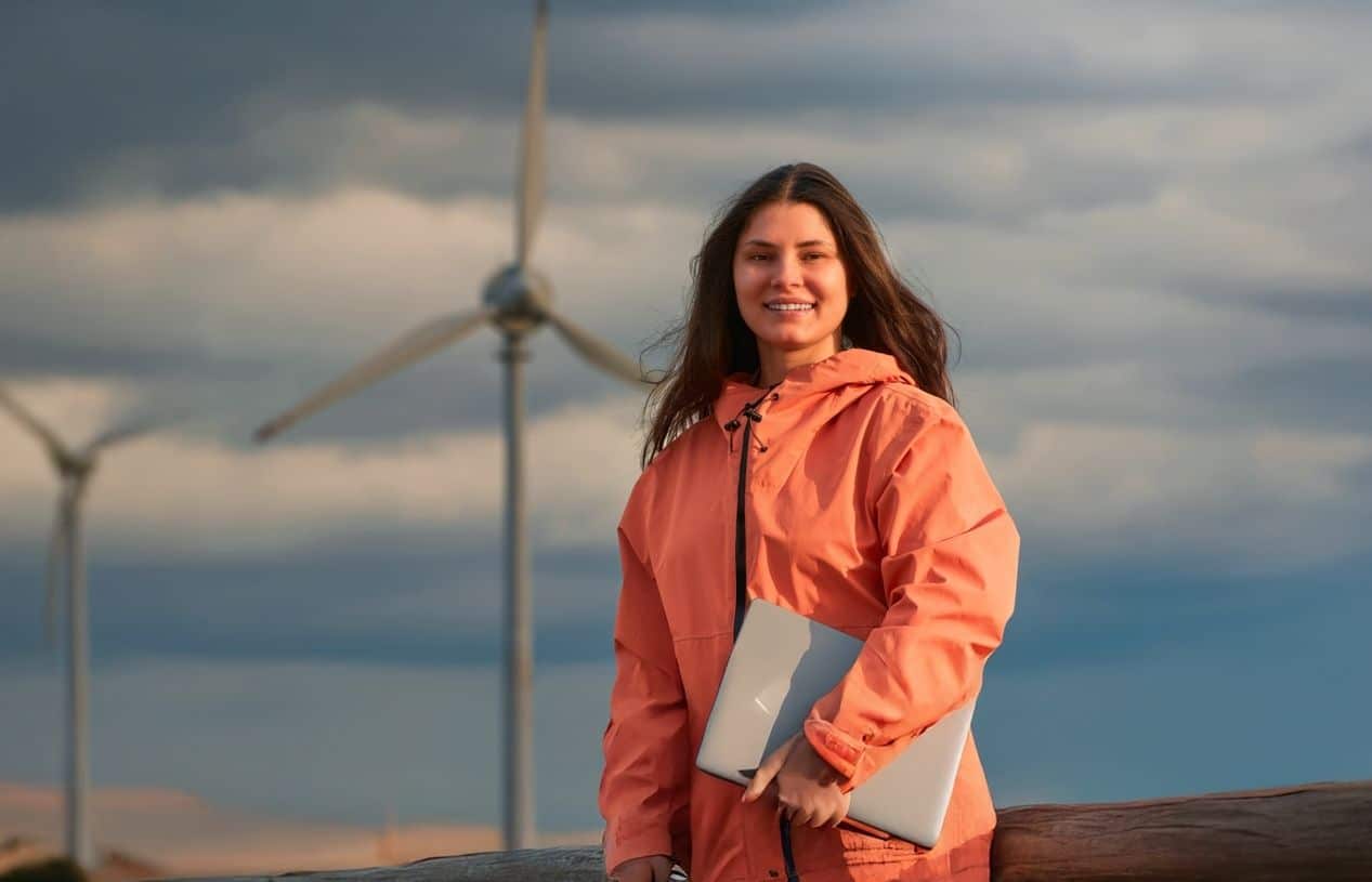 Étudiante en énergie renouvelable devant des éoliennes illustrant la transition énergétique