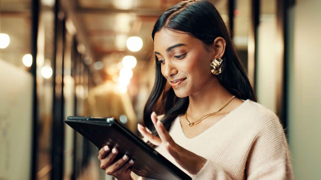 Jeune professionnelle consultant des offres d’emploi sur tablette dans un environnement de travail moderne