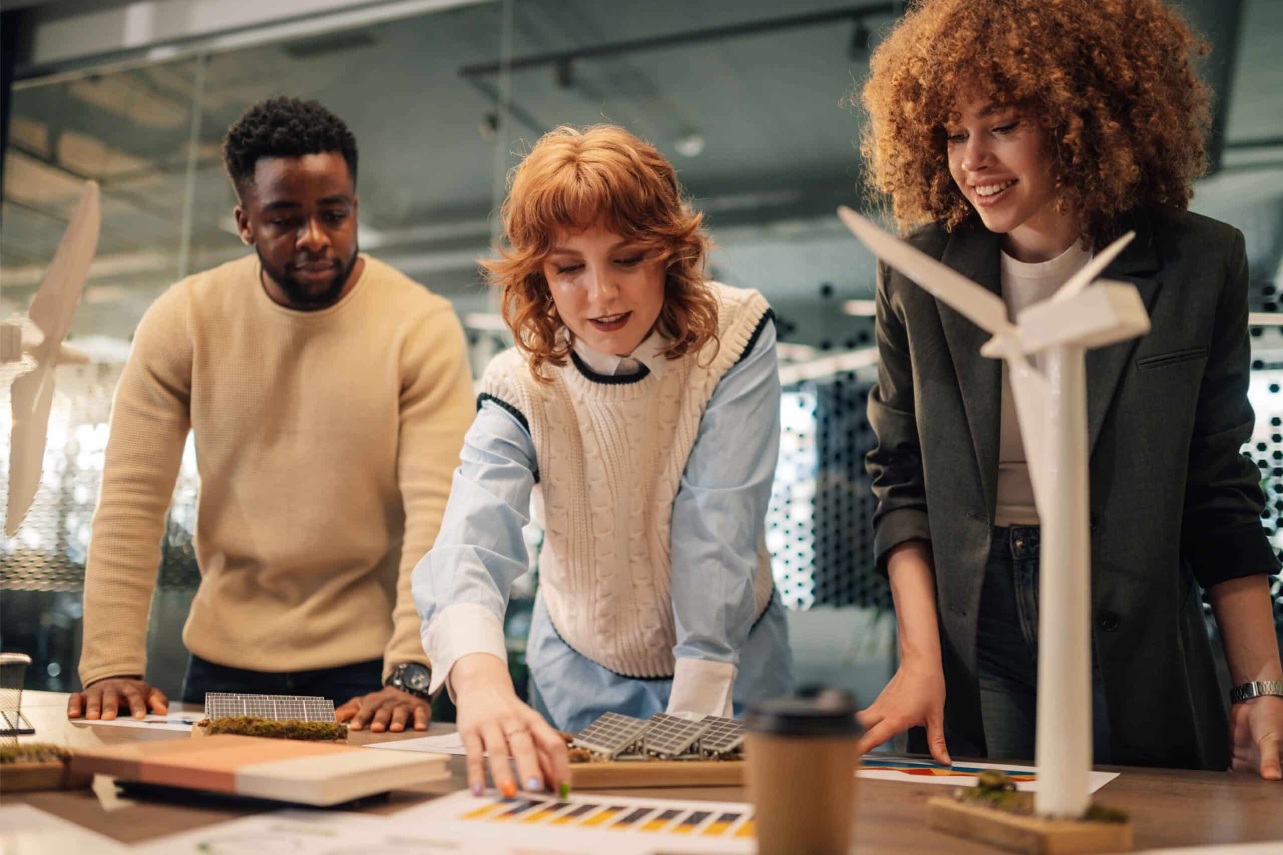 Étudiants travaillant en équipe sur un projet d’énergie avec maquettes d’éolienne et panneaux solaires, illustrant les débouchés dans les secteurs de l’énergie, de l’ingénierie et des technologies